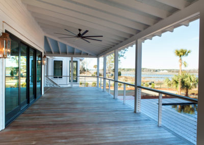 Rear porch of custom Johns Island home, with Dark-bottomed swimming pool with tabby decking blends in with the natural surroundings, overlooking the marsh